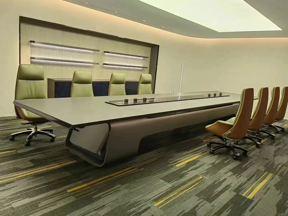 Large executive conference table with built-in power panel in a modern boardroom, flanked by tan leather chairs.