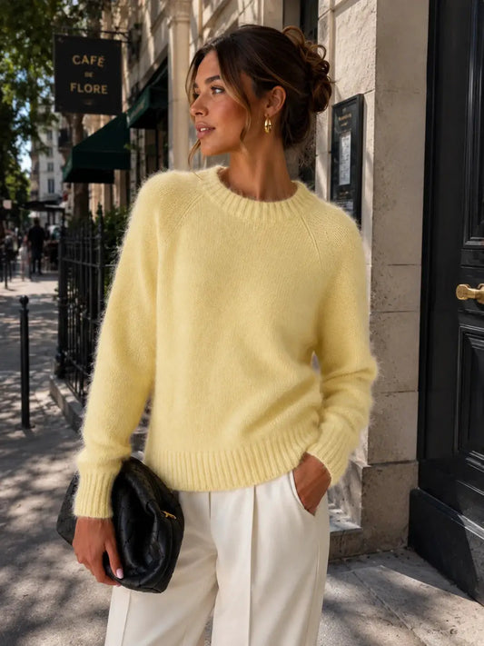 Womens soft cozy knit sweater in pale yellow with fluffy texture, paired with cream trousers and a black quilted clutch.
