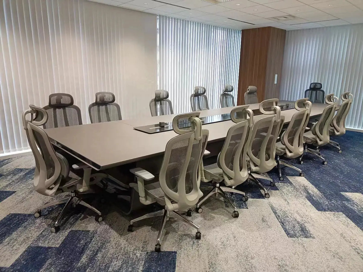 Large modern executive conference table with gray mesh chairs in a boardroom.