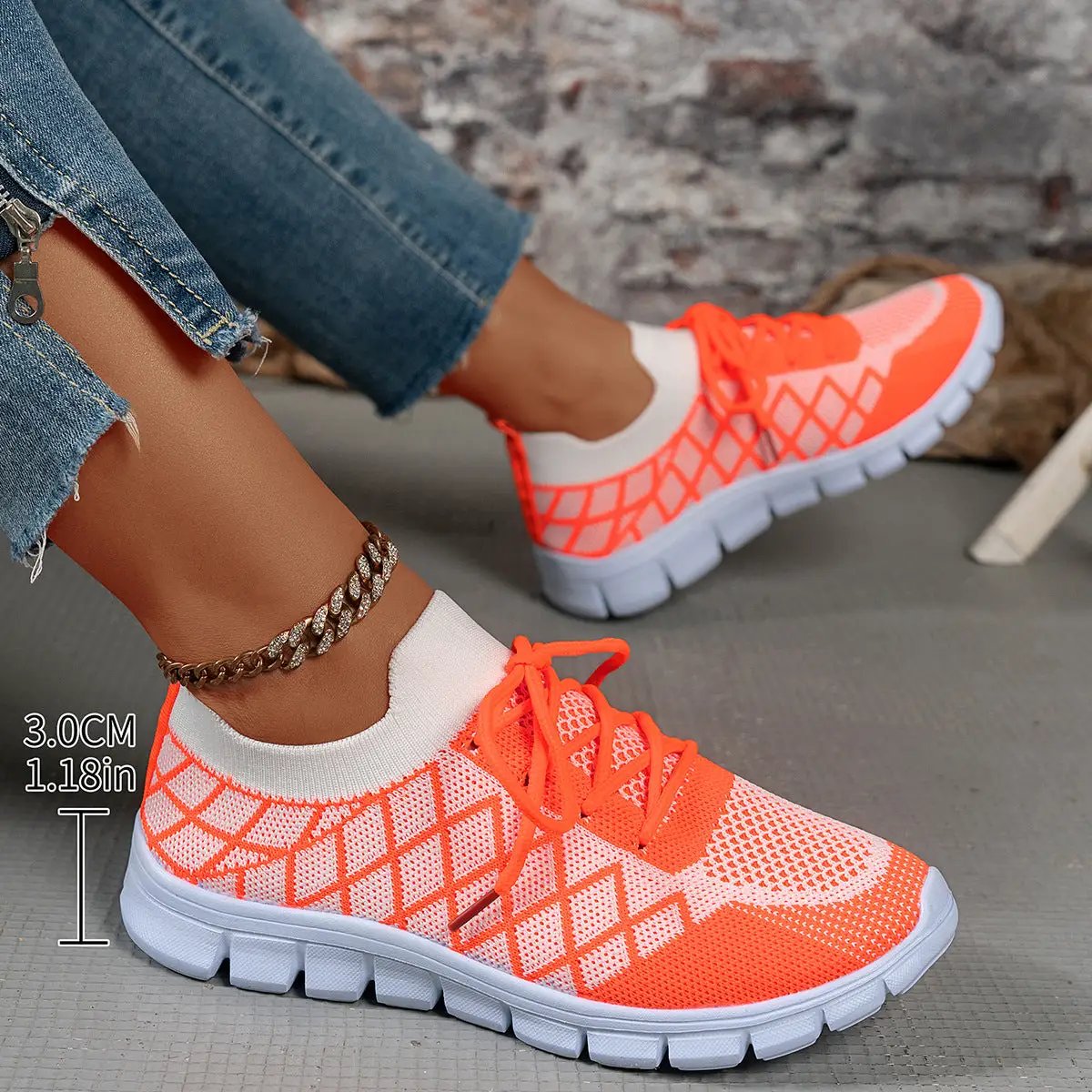 Pair of colorblock lace-up flyknit sneakers in neon orange and white mesh.