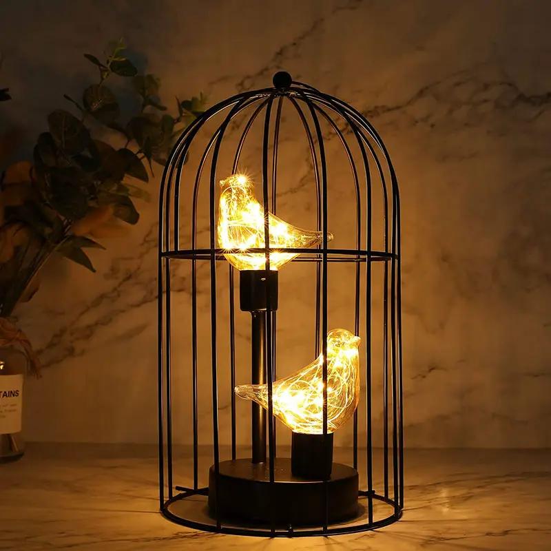 Birdcage lamp with two warm LED-lit birds inside, 12-inch tall, black metal, battery-operated