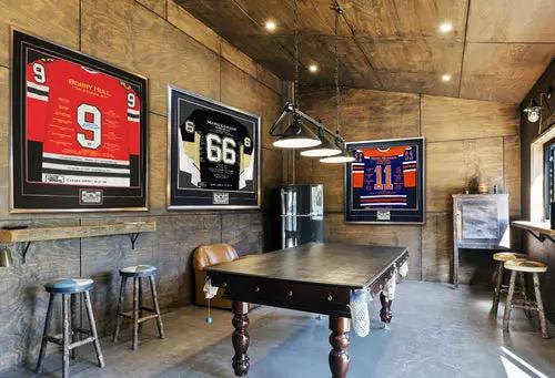 Paul Coffey career jersey autographed; three framed hockey jerseys on wood-paneled wall by pool table