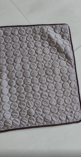 Dog cooling mat for pets; beige quilted pad with circular bubble pattern and brown border.