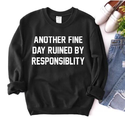 Another Fine Day Sweatshirt, black with bold white text reading ANOTHER FINE DAY RUINED BY RESPONSIBILITY, with jeans.