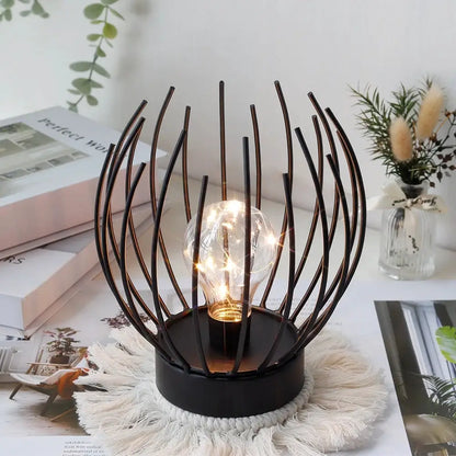 7-inch tall battery-powered table lamp with a black metal orb frame around a glowing filament bulb
